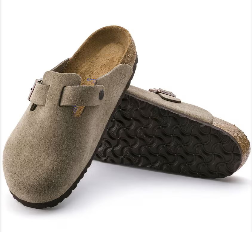 Pair of brown suede clogs with black soles on a white background